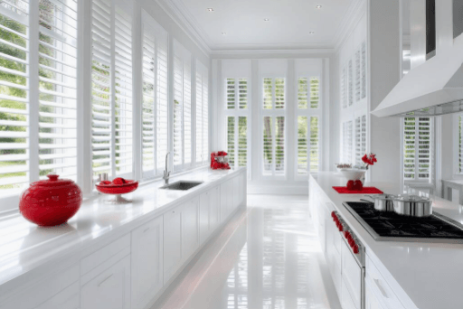 White kitchen lined with white plantation shutters on every window